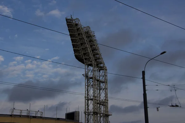 Constructions of the soccer field lighting system against the sky