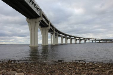 Otobandaki körfezin kıyısından, kavis üzerinde yürürken, desteklerin ve ön plandaki geçitin gökyüzüne yakın görüntüsünü al