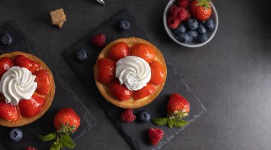 Ev yapımı organik çilek turtası, ahududu ve mavi böğürtlenli ve koyu arkaplan manzaralı kahve..