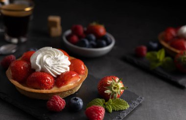 Ev yapımı organik çilekli turta, ahududu ve koyu arkaplanda kahve..