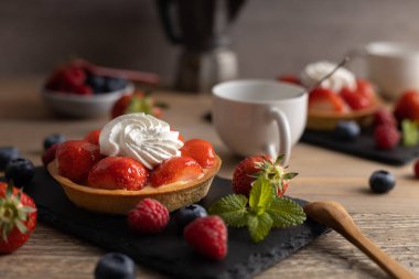 Ev yapımı organik çilekli turta ahududu ve ahşap bir masada kahve..