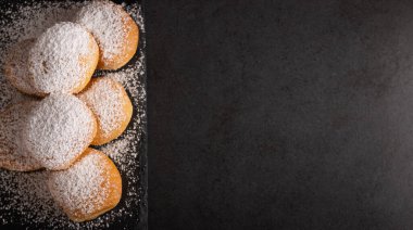 Koyu arkaplanda şekerle kaplı ev yapımı kızarmış tatlı börekler.