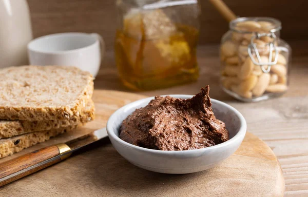 Homemade vegan chocolate spread in a small bowl made of almond butter,cacao and honey.