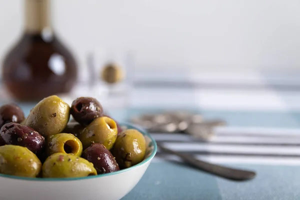 Organic Greek olives in a bowl on a blue and white background