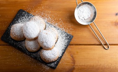 Tahta bir masada şekerle kaplı ev yapımı kızarmış tatlı börekler..