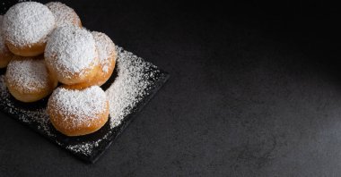 Koyu arkaplanda şekerle kaplı ev yapımı kızarmış tatlı börekler.