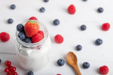Kahvaltı masasında çilekli yoğurt, ahududu ve yaban mersini. Beyaz arkaplan üst görünümünde izole edilmiş