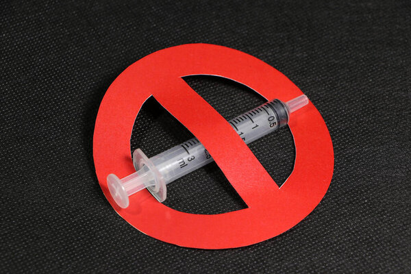 A syringe with symbolic of no or anti in red color on black background.