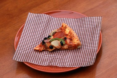 Kahverengi viski kağıdında, kahverengi yuvarlak tabakta, ahşap zeminde, üçgen bir pizzacı..