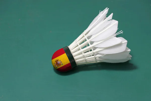 使用的羽毛球和头上涂有西班牙国旗 将水平放置在羽毛球场的绿色地板上 羽毛球运动概念 — 图库照片