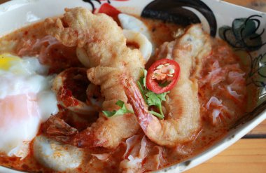 Tom Yum Goong Baharatlı Baharatlı Çorba, kızarmış karides ve tahta masadaki oval kasede lav yumurtası..