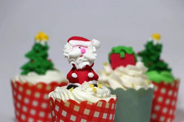 Christmas cupcakes decorated with Santa Claus and out focus Christmas cupcakes on white background.