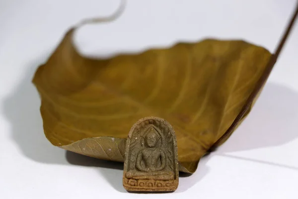 白い床に乾いた茶色の神聖なイチジクや菩提樹の葉で小さな仏像のお守り 心臓へのアンカーの使用 — ストック写真