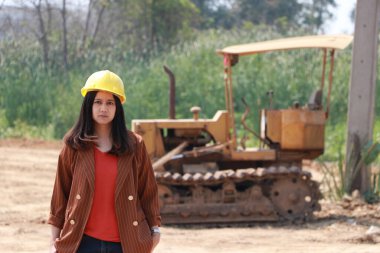 İnşaat mühendisi ya da mimar, iş yerindeki ön yükleme mühendisi inşaat aracının arka planında duran ve pantolon cebi olan kadın mimar..