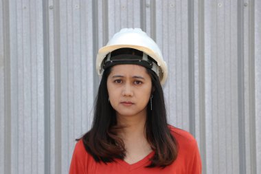 Kadın inşaat mühendisi ya da mimar Metal levha arka planında duran beyaz kaskı giyer..