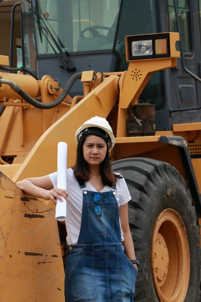 女性土木工程师或建筑师 戴着白色头盔和工程图纸 手握合金推土机卡车和前置载货卡车在工作区施工汽车 — 图库照片