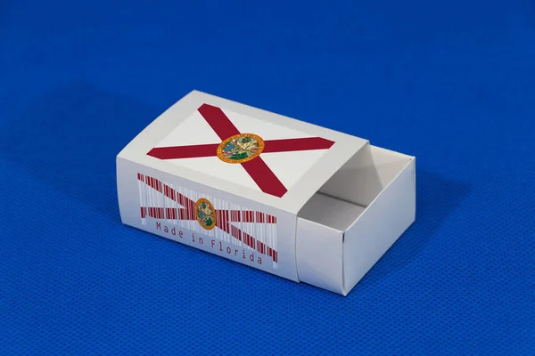 バーコードと青の背景に国旗の色を持つ白い箱にフロリダフラグは 試合や製品を置くための紙の包装 フロリダからの輸出貿易の概念 — ストック写真