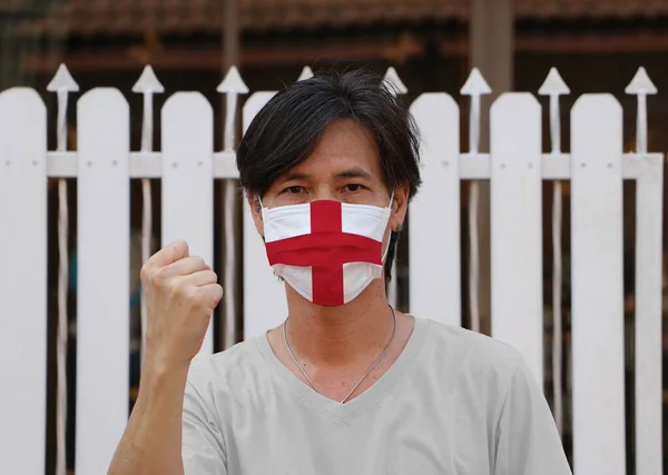 英国国旗戴在卫生面具上 这个人戴上面具防止细菌滋生 微小颗粒保护或病毒电晕或Covid19 举起拳头表示战斗或与疾病作斗争的概念 — 图库照片
