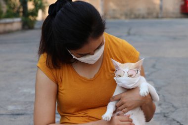 Maskeli Asyalı kadın ve gözlüklü kedisi mikropları engelliyor. Küçük Parçacık ya da virüs koronası ya da Covid-19 koruması. 