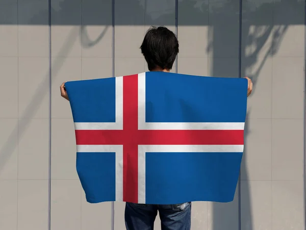 Homem Está Segurando Bandeira Islândia Seu Ombro Voltar Fundo Cinza — Fotografia de Stock