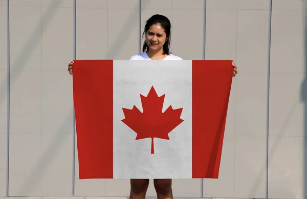 漂亮的女士手里拿着加拿大国旗 有着灰色的背景 — 图库照片