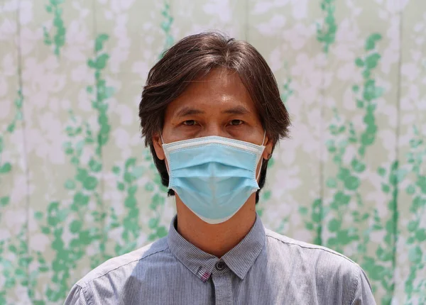Masked Asian man prevent germs and wear blue shirt. Tiny Particle or virus corona or Covid 19 protection. Concept of Combating illness.