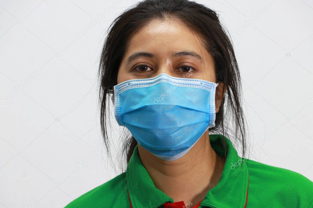 Masked Asian woman prevent germs and wear green shirt. Tiny Particle or virus corona or Covid 19 protection. Concept of Combating illness.