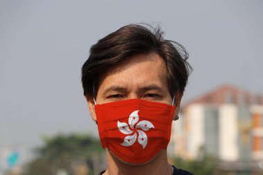 Hong Kong bayrağı hijyen maskesinde. Maskeli Asyalı adam mikropları engeller. Minik Parçacık Koruma Konsepti veya virüs koronası veya Covid-19.