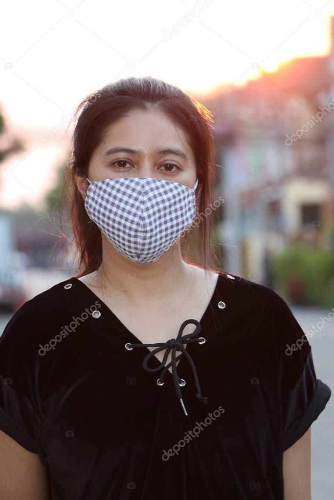 Masked Asian woman prevent germs and wear black clothing. Tiny Particle or virus corona or Covid 19 protection. Concept of Combating illness.