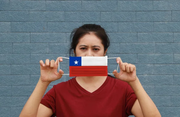 A woman and hygienic mask with Chile flag pattern in her hand and raises it to cover her face. A mask is a very good protection from Tiny Particle or virus corona or Covid 19.