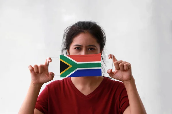 A woman and hygienic mask with South Africa flag pattern in her hand and raises it to cover her face. A mask is a very good protection from Tiny Particle or virus corona or Covid 19.