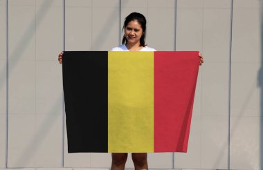 Güzel bayan gri arka planda Belçika bayrağını tutuyor..