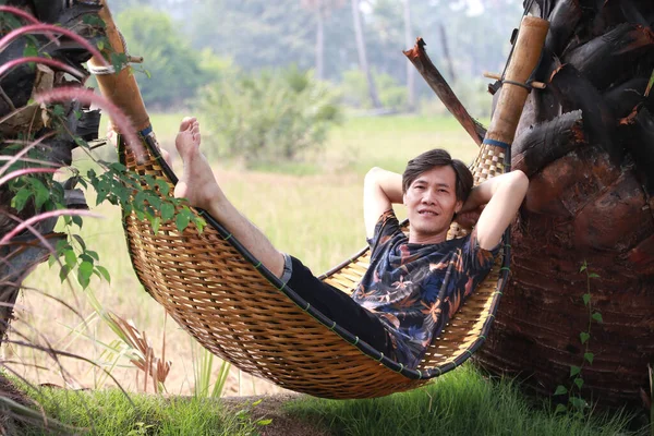 Agriculturist male lying relaxed in the basketry crib on the nature.