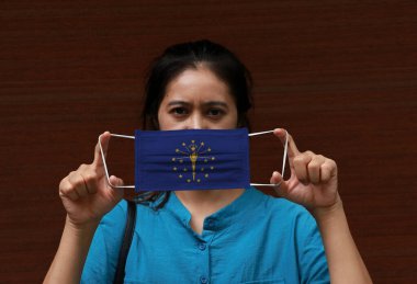 Elinde Indiana bayrağı deseni olan bir kadın ve hijyenik maske yüzünü kapatmak için kaldırıyor. Maske, Tiny Partikül veya virüs koronası veya Covid 19 'a karşı çok iyi bir korumadır..