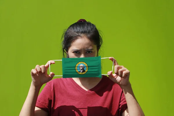 A woman and hygienic mask with Washington flag pattern in her hand and raises it to cover her face. A mask is a very good protection from Tiny Particle or virus corona or Covid 19.