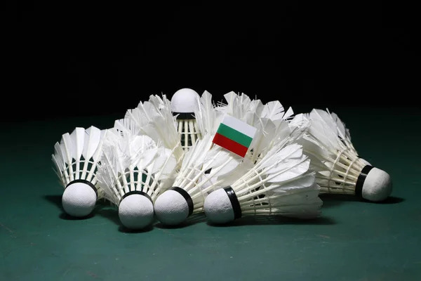 Mini Bulgaria flag stick on the heap of used shuttlecocks on green floor of Badminton court with dark black background.