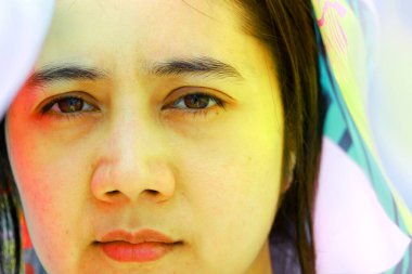 Yüzünde kumaştan rengarenk bir yansıma olan güzel bayanın yüzü. Kadın yüzünde kırmızı ve sarı renk.