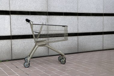 Yerde gri ve yatay siyah çizgili alışveriş arabası var. Tramvay, bir dükkan tarafından, özellikle süpermarketler tarafından, dükkanın içindeki müşteriler tarafından alışveriş sırasında kasaya taşınması için sağlanan bir arabadır..