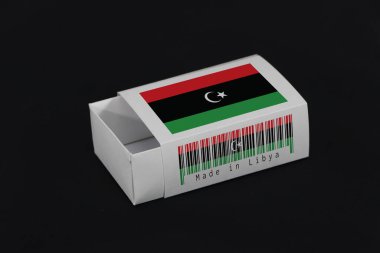 Beyaz barkodlu Libya bayrağı ve siyah arkaplandaki ulus bayrağı, maç veya ürün koymak için kağıt ambalajı. Libya 'dan ihracat ticareti kavramı.