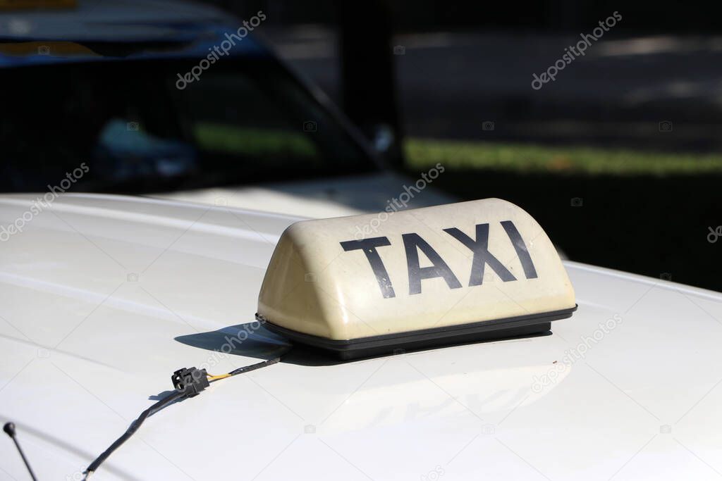 Taxi light sign or cab sign in drab white color with black text on the car roof at the street blurred background, Myanmar.