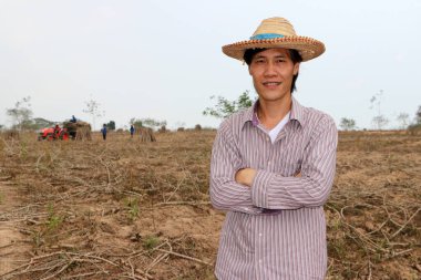 Erkek çiftçi kasava çiftliğinde dikilip sarılıyor. Odak traktörü ve işçi olmadan..