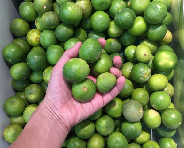 Elinde yeşil kireç ve arka planda bir yığın kireç. Limona benzeyen yuvarlak bir narenciye. Ama daha yeşil, daha küçük ve kendine özgü asit aromalı..