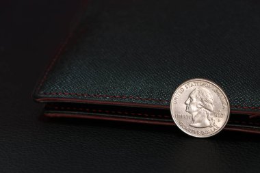 Siyah zemin üzerinde siyah cüzdan bulunan ABD Doları bozukluklarının dörtte biri, finans kavramı.