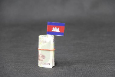 100 Kamboçya Riel 'ı. Koyu gri zemin ve arka planda mini Kamboçya bayrağı. Finans sektörü kavramı.