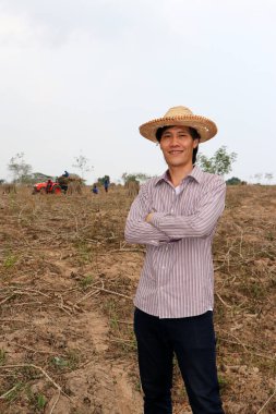 Erkek çiftçi kasava çiftliğinde dikilip sarılıyor. Odak traktörü ve işçi olmadan..