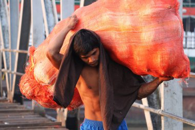 Yangon, Myanmar, 24 Şubat 2019: Myanmese işçisi gemiden hindistan cevizi kabuğu taşıyor ve Yangon Nehri 'ndeki liman köprüsünü geçiyor.