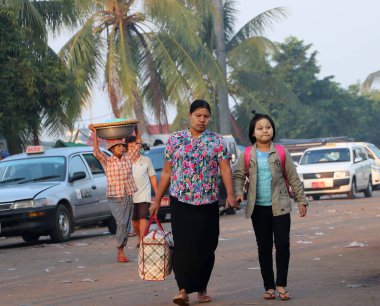 Yangon, Myanmar, 24 Şubat 2019: Yüzünde thanakha (Myanmar pudrası) olan Myanmese 'li kadın çantayı sabah markete gitmek üzere taşıyor.