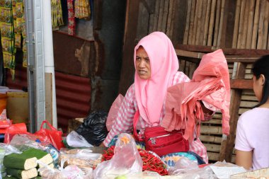 Jakarta, Endonezya 6 Mayıs 2019: Endonezyalı Müslüman kadın sebze satıcısı peçe takıyor ve Muara Angke limanındaki pazarda sebze satıyor.
