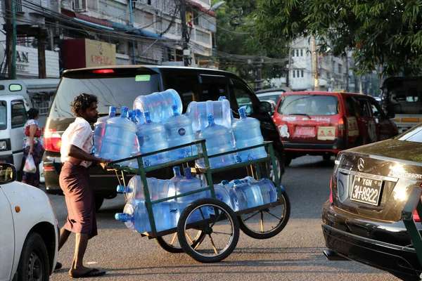 Yangon, Myanmar, Feb 20, 2019: Myanmese worker man pushing the three wheel of water tanker barrow on the street at Yangon.