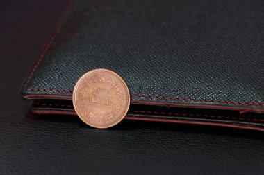 Siyah zemin üzerinde siyah cüzdanı olan on Japon Yen (JPY) madeni para, finans kavramı.